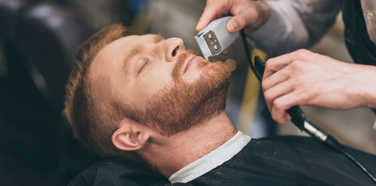 barber trimming man's beard