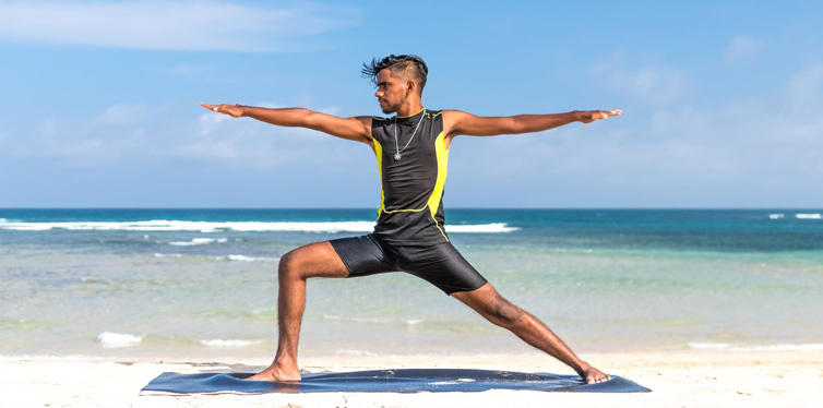 man doing yoga at the beach