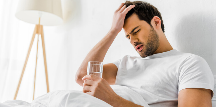 man with headache holding glass of water