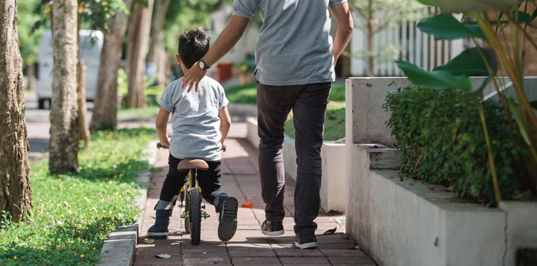 dad teaching his son how to ride a bike