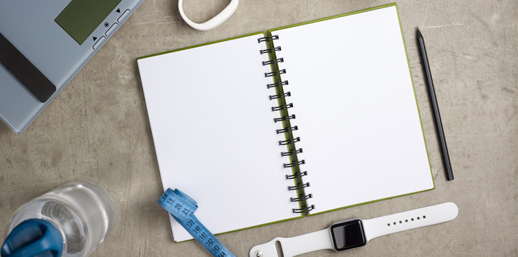 notebook, fitnesss tracker and dumbbell