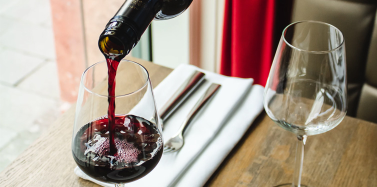 person pouring wine into a glass