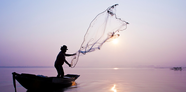 man throwing fishing net into the water