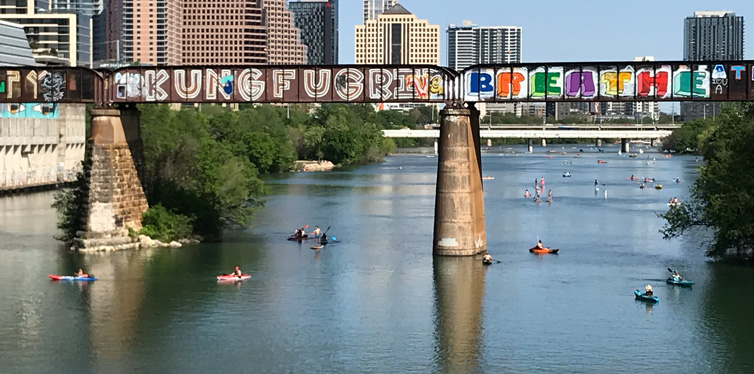people in kayaks under the bridge