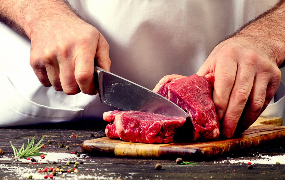 man cutting meat with a butcher knife