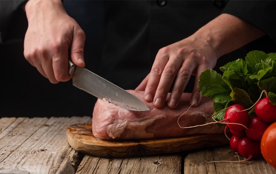 man using butcher knife to cut raw meat
