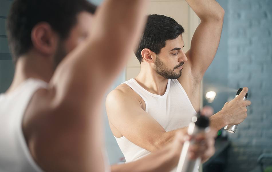 man using spray deodorant