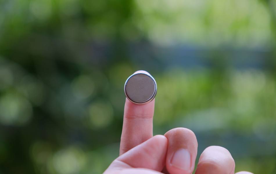 man holding a cr2032 battery