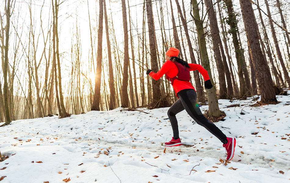 woman running through woods in winter