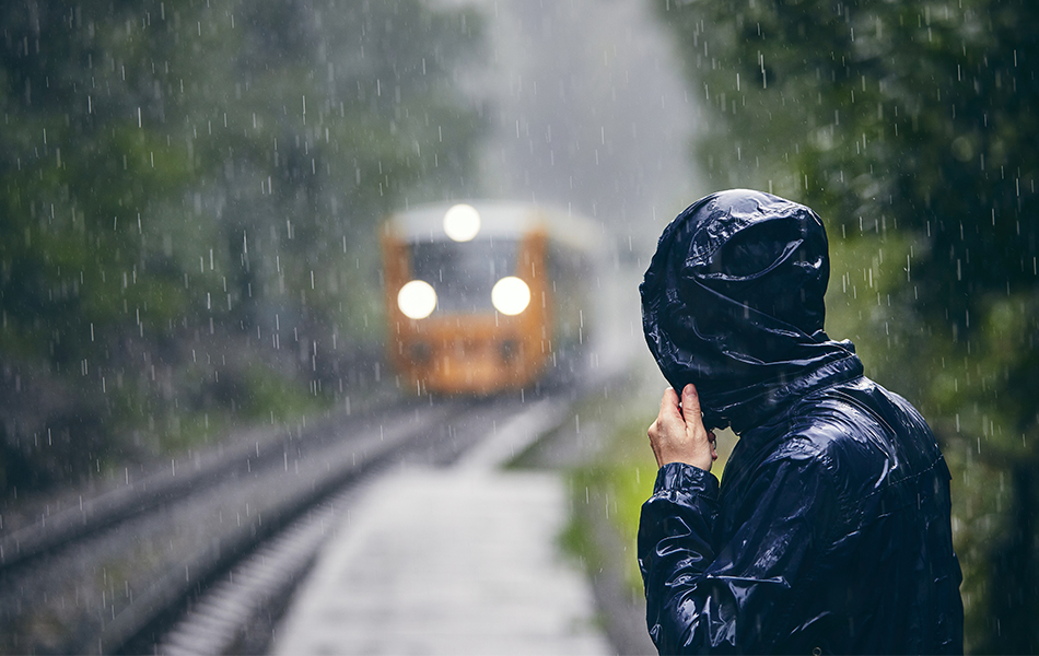 man in jacket standing in heavy rain