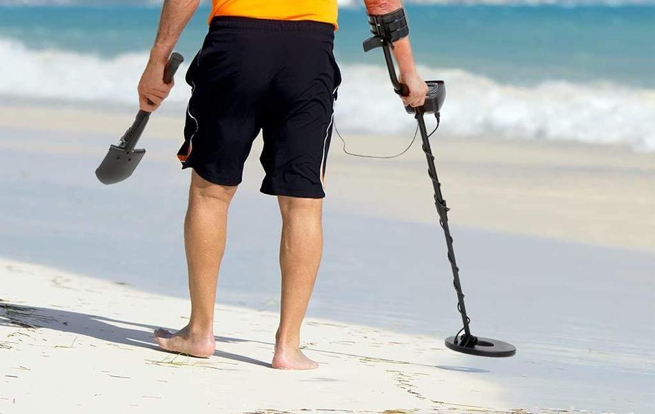 men using metal detector on the beach