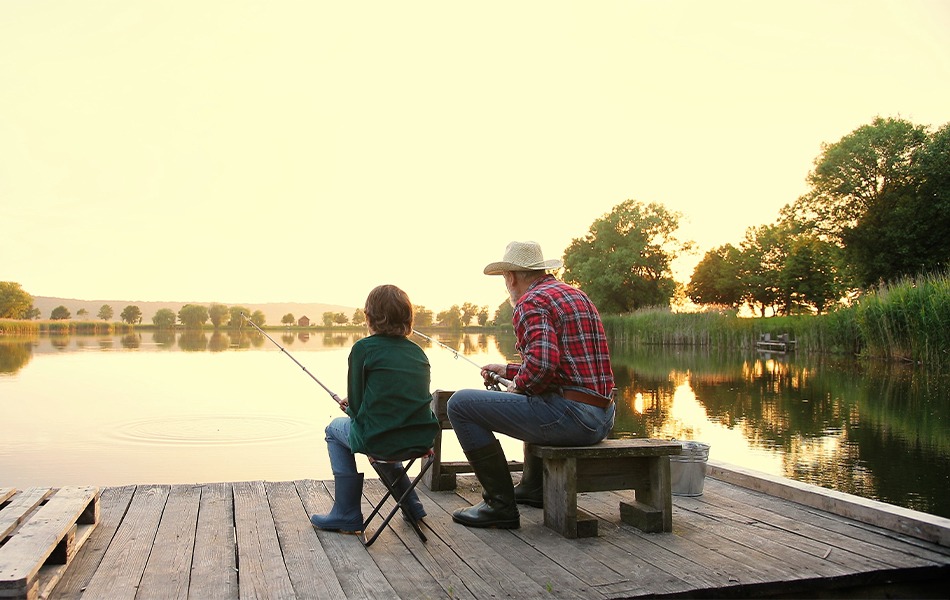 man wearing fishing hat is fishing with his grandson